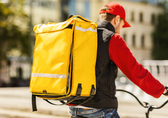 Unrecognizable Courier Delivering Food In Yellow Backpack Riding Bike Outside