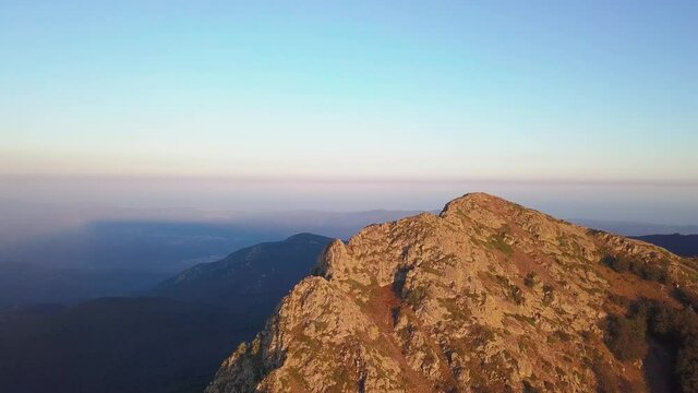 Aerial drone shot orbiting a rocky mountain peak named "Les Agudes" during sunset. Montseny, Barcelona, Spain.