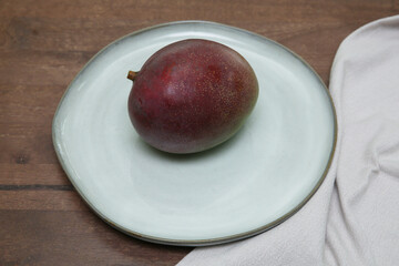 organic fresh red mango on a plate on a wooden table with with a tissue napkin