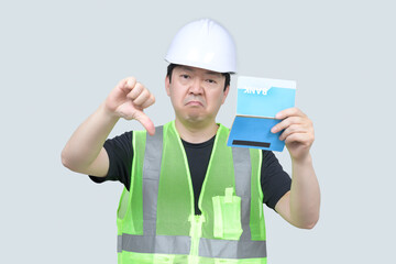 A middle-aged Asian engineer holding a bank passbook in his hand on a gray background.