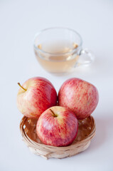 Three red apples in a wicker plate a transparent Cup of Apple juice on a white background