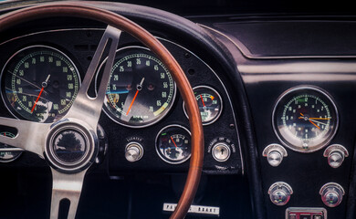 Part of the interior of an oldtimer luxury sports car with steering wheel, speedometer, fuel, clock...