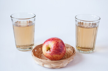 Two glasses of Apple juice and a red Apple on a white background