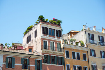 Fototapeta na wymiar Lively and vibrant italian rooftops of Rome in front of clear light blue sky.