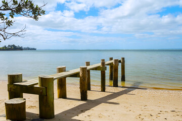 Fototapeta na wymiar Small Wooden Wharf at Awhitu Regional Park Beach during Low Tide; Kauritutahi Beach; Auckland New Zealand