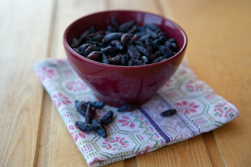 honeysuckle berries in a maroon Cup with a brown towel on the wooden table
