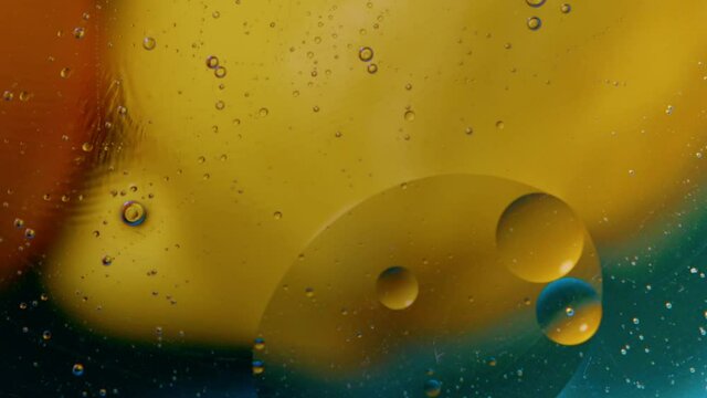 High quality abstract close-up 4k slow motion video of a bright colourful natural bacground with lemons and oranges giving orange blue and yellow colours with the water and oil bubbles moving around