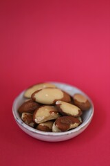 Fototapeta premium Brazil nut in a ceramic gray cup on a bright pink fuchsia background. Wholesome food and snack. Healthy fats ingredient. Vegetarian and vegan food.keto 