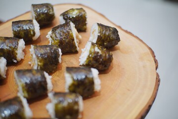 Close up of sushi on top of a wooden plate