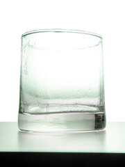 Crystal glass with water droplets resting on the table on a white background
