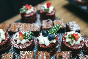Chocolate biscuit cakes with whipped cream blueberry - strawberry and mint leaf topping served on black slate
