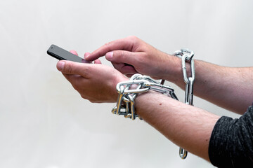 Close-up of Man holding smartphone with metal chain on white studio background. concept security of...