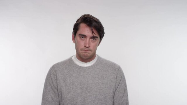 Portrait of an upset depressed man with his head down on a while studio backdrop