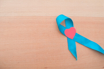 blue ribbon on a wooden background. hand holds blue awareness ribbon and a blood. World Diabetes...