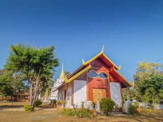 view of buddhist temple design with glasses window around with green forest and blue sky background, Wat Chan Temple, famous attraction in Kalayaniwattana District, Chiang Mai, northern of Thailand.