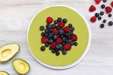 Tasty homemade avocado and lime Raw Cake with blueberries and raspberries, healthy vegan recipes