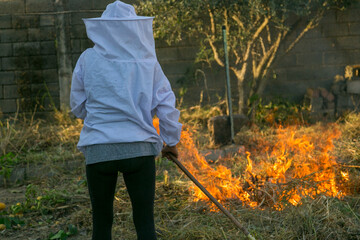 Apicultor controlando las llamas de fuego para hacer humo con las hierbas secas