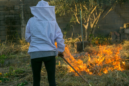 Apicultor controlando las llamas de fuego para hacer humo con las hierbas secas
