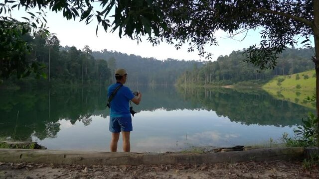 Hiker taking a photo of lake and forest view by the side of the lake. Breathtaking and beautiful landscape view.