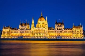 Naklejka premium Hungarian Parliament lit at night during blue hour, view from across the Danube river, Budapest, Hungary