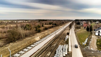 Zabiezki, Poland, 2020. Aerial view on railway line construction site in small village near Otwock and Warsaw. Railway components ready to deploy. Train tracks underlay and concrete ties.