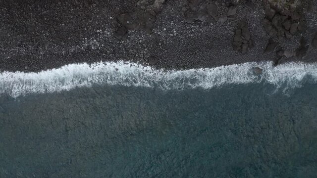 Aerial of breaking waves on a volcanic Island moving out to the Ocean