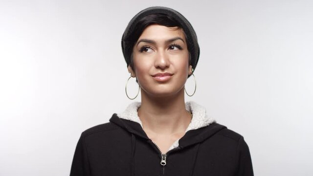 Portrait of a young woman of Middle Eastern descent looking up and smiling on a white studio backdrop