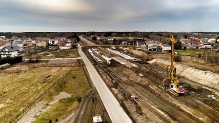 Fototapeta premium Zabiezki, Poland, 2020. Aerial view on railway line construction site in small village near Otwock and Warsaw. Railway components ready to deploy. Train tracks underlay and concrete ties.