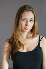 Fototapeta premium Portrait of an attractive teenage girl wearing a camisole posing looking at the camera on grey background
