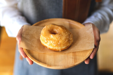 A waitress holding and serving a piece of homemade donut in wooden tray