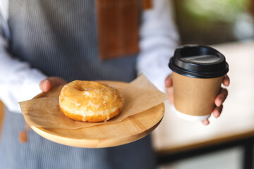 A waitress holding and serving a piece of homemade donut in wooden tray and a paper cup of coffee