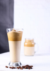 Dalgona coffee in a glass with dried coffee on white table