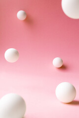 Levitation white abstract spheres on pink background with selective focus, front view. Backdrop template for cosmetic product or beauty fashion presentation, vertical