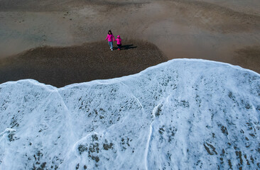 ドローンで空撮冬の海の砂浜で遊んでいる親子