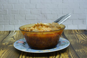 Indonesian traditional meatballs or bakso. Soup containing meatballs, noodles isolated on wood background