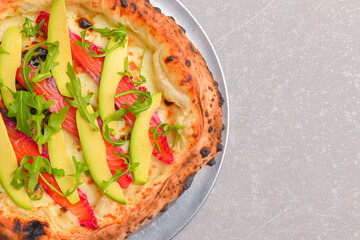 Close-up of a delicious smoked salmon pizza with cheese, avocado and smoked salmon. Sea-food.