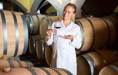 Female wine house worker checking quality of product