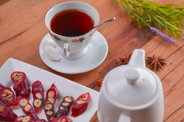 Tasty oriental sweets. Caucasian delicacy churchkhela - georgian nut treats. Served with a glass of tea and a tea pot.