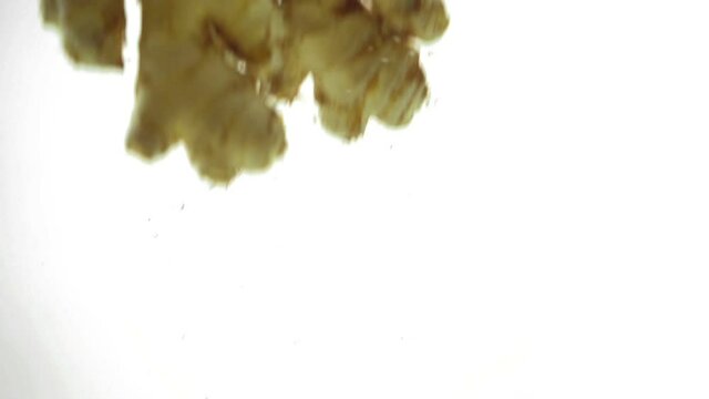 Fresh ginger dropping into water.