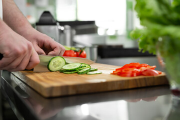 Chef in the kitchen cuts fresh and delicious vegetables for a vegetable salad