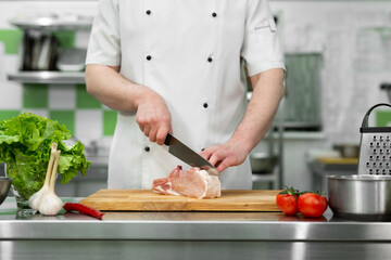 Chef cutting the meat on a wooden board