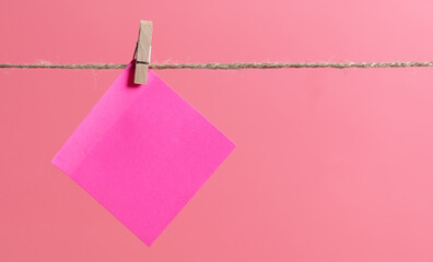 Pink piece of paper hanging on a rope on a pink