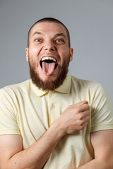 Close-up portrait of a young happy man in a yellow T-shirt, emotions on a gray background. isolated