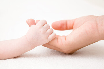 Baby hand clinging young mother fingers. Closeup. Lovely, emotional, sentimental moment. Family...