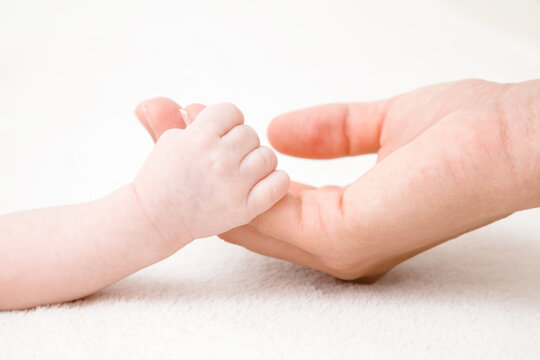 Baby hand clinging young mother fingers. Closeup. Lovely, emotional, sentimental moment. Family concept.