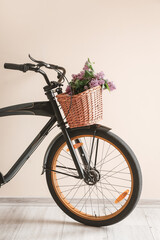 Fototapeta na wymiar Modern bicycle and wicker basket with flowers near light wall