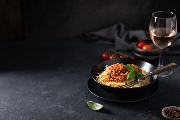 Italian pasta. Spaghetti bolognese in a black plate on a dark background. Place for text