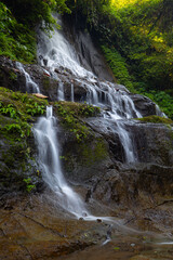 Naklejka na ściany i meble Waterfall landscape. Beautiful hidden Goa Giri Campuhan waterfall in tropical rainforest in Bali. Nature concept. Slow shutter speed, motion photography.