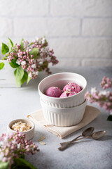 lilac ice cream in a white bowl. In the background is a pink lilac. 