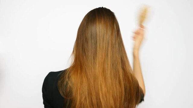 A young beautiful woman combs her long luxurious hair